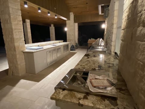 Modern bathroom under construction with white cabinetry, recessed lighting, and natural stone tile flooring at night