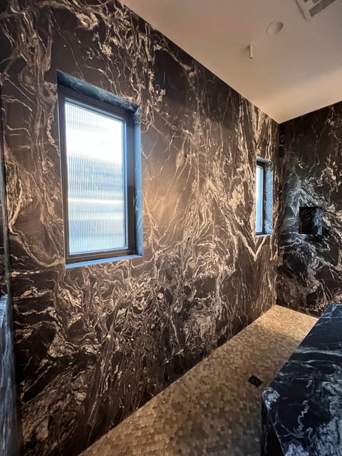 Modern hallway with dark marble walls, two blue-framed windows, and tiled floor