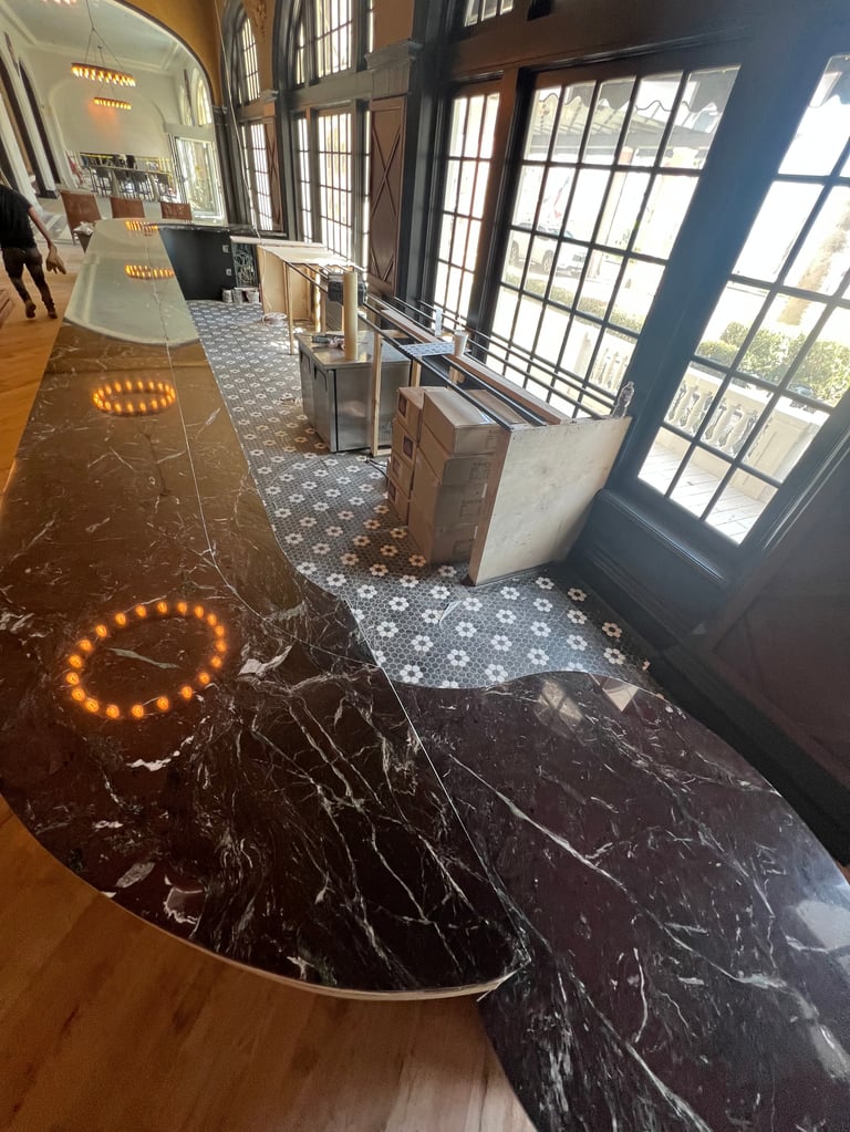 Modern interior hallway with black marble flooring, illuminated circular floor lights, large windows, and transitioning tile patterns